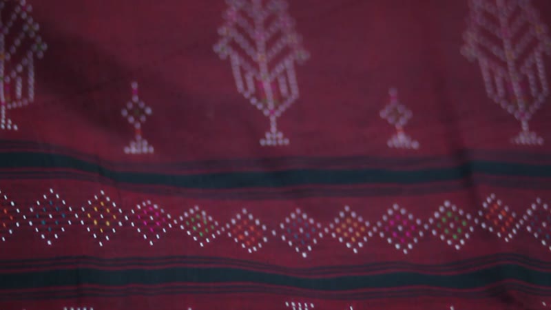 Deep red cloth patterned with rows of raised white dots